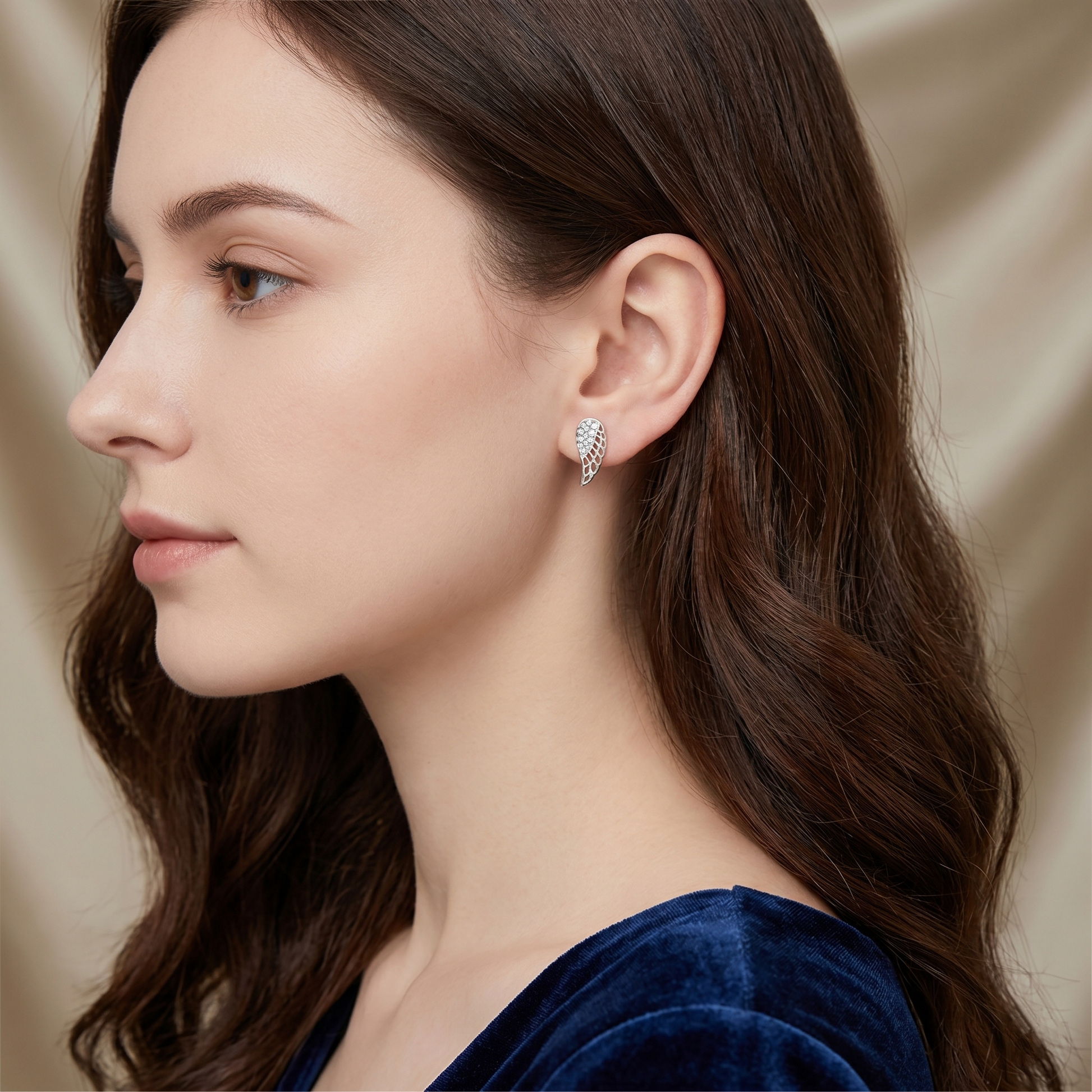 Angel wing stud earrings on ear, paved half-wing motif in silver tone