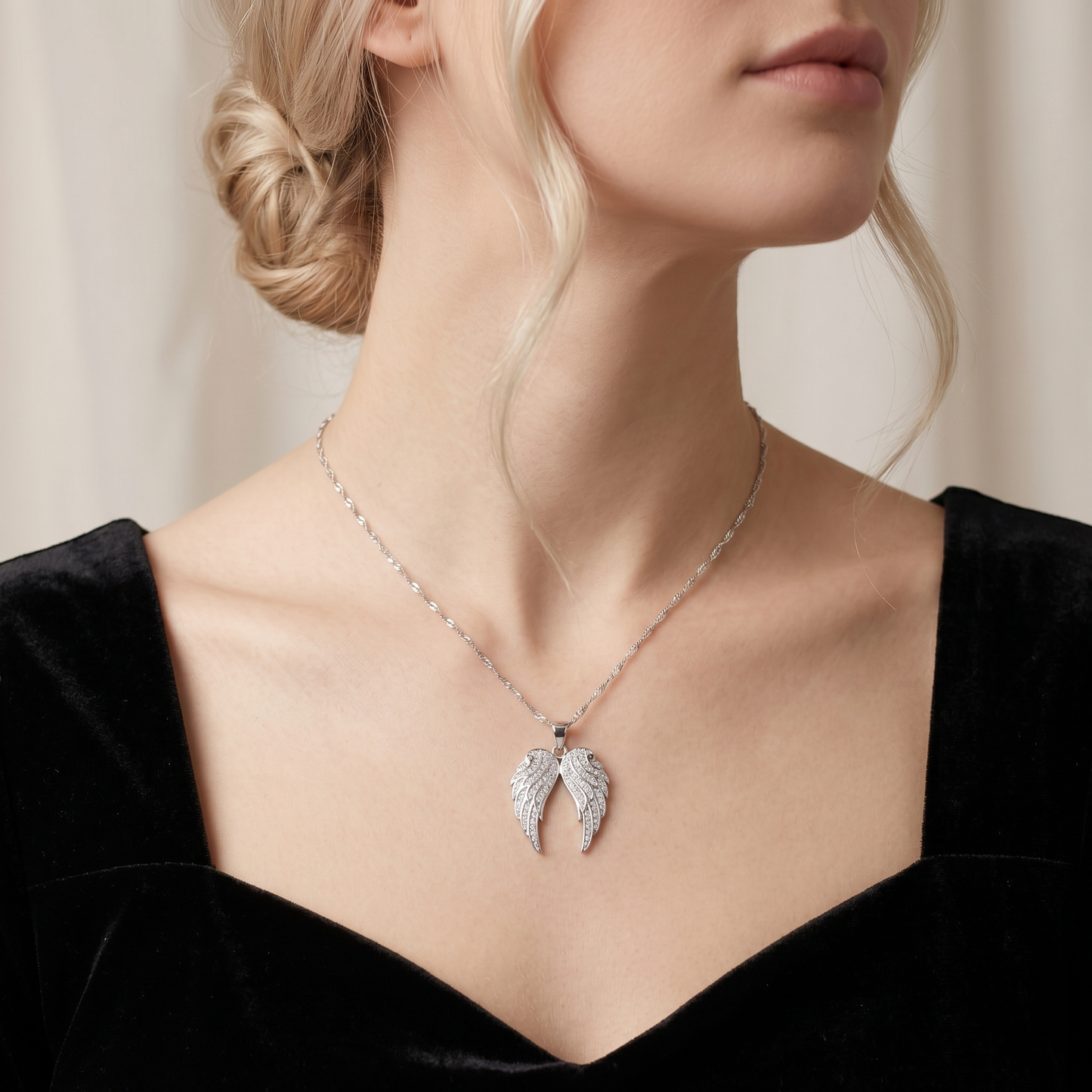 Angel wing pendant necklace with pavé feather wings, shown at neckline